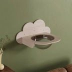 Wolkenfoermiger Katzenwand Schlafplatz mit runder Liegemulde aus Massivholz, montiert an gruener Wand mit Pflanze im Wohnzimmer
