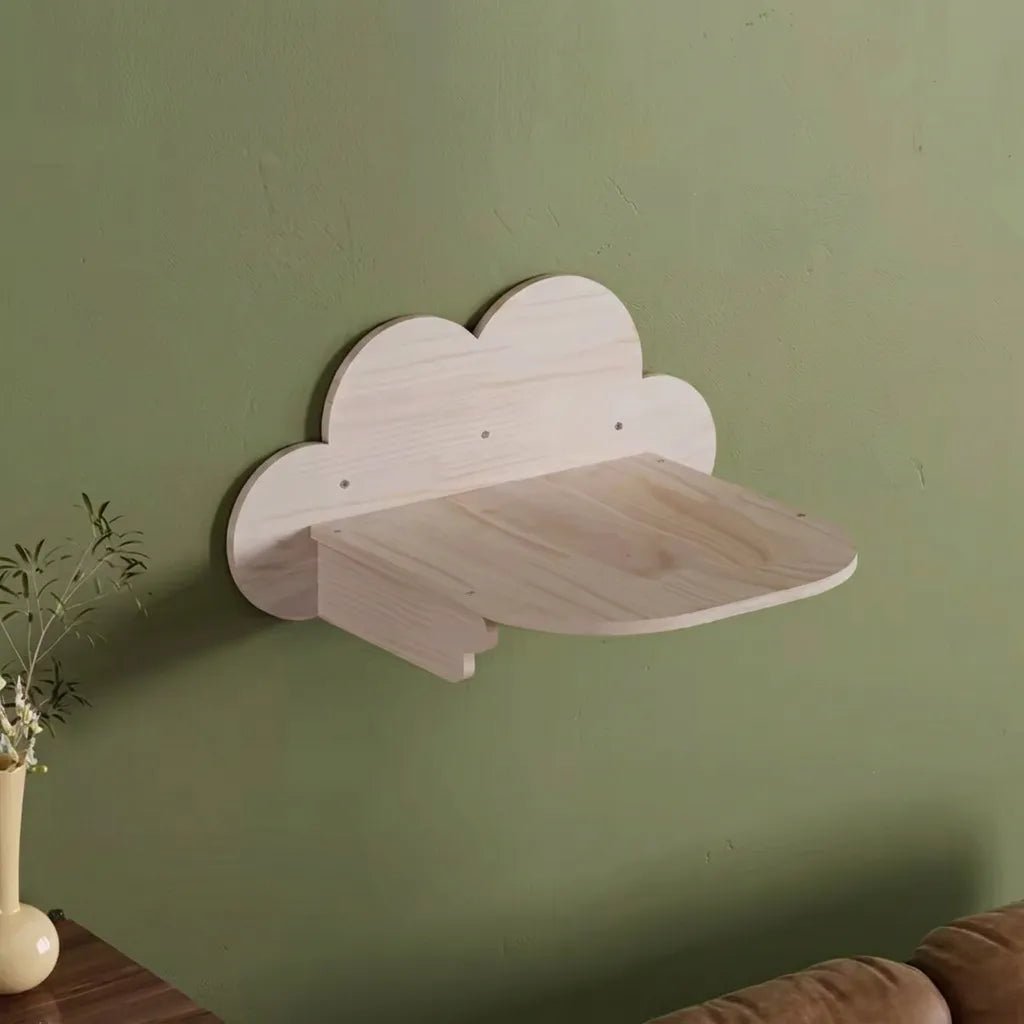 Wolkenfoermiges Katzenwand Regal aus hellem Massivholz, montiert an gruener Wand mit Pflanze im Wohnzimmer
